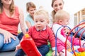 Group of happy young mothers watching their cute and healthy babies play Royalty Free Stock Photo