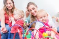 Group of happy young mothers watching their cute and healthy babies play Royalty Free Stock Photo