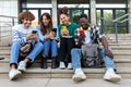 Multiracial college student friends look mobile phone laughing together. University students using smartphone outdoors. Royalty Free Stock Photo