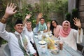 Group happy young muslim waving at table dining during ramadan c