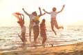 Group of happy young people dancing at the beach on beautiful summer sunset Royalty Free Stock Photo