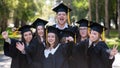 Group of happy young people in graduation gowns outdoors. Students are walking in the park. Royalty Free Stock Photo