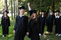 Group of happy young people in graduation gowns outdoors. Students are walking in the park. Royalty Free Stock Photo