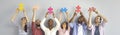 Group of happy young people holding pieces of jigsaw puzzle standing against light background