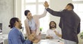 Group of happy young people making a business deal and giving each other a high five Royalty Free Stock Photo