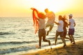 Group of happy young people is running on background of sunset beach and sea Royalty Free Stock Photo