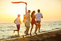 Group of happy young people is running on background of sunset beach and sea Royalty Free Stock Photo