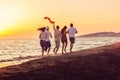 Group of happy young people is running on background of sunset beach and sea Royalty Free Stock Photo