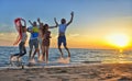 Group of happy young people is running on background of sunset beach and sea Royalty Free Stock Photo