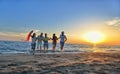 Group of happy young people is running on background of sunset beach and sea Royalty Free Stock Photo