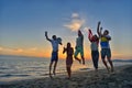 Group of happy young people is running on background of sunset beach and sea Royalty Free Stock Photo