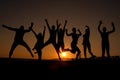Group of happy young people silhouettes jumping on the beach  on beautiful summer sunset Royalty Free Stock Photo