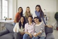 Group of happy young women sitting on couch, enjoying tea, smiling and looking at camera Royalty Free Stock Photo