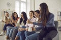 Group of happy young women sitting on sofa, drinking coffee, chatting and laughing Royalty Free Stock Photo