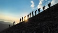 Group of harmonious mountaineers hiking to the summit at sunrise