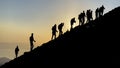 Group of harmonious mountaineers hiking to the summit at sunrise