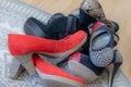 Group of high heel shoes of different designs piled up on a gray carpet