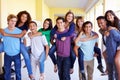 Group Of High School Students Giving Piggybacks In Corridor