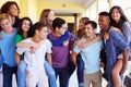 Group Of High School Students Giving Piggybacks In Corridor