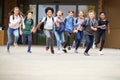 Group Of High School Students Running Out Of School Buildings Towards Camera At The End Of Class Royalty Free Stock Photo