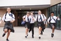 Group Of High School Students Wearing Uniform Running Out Of School Buildings Towards Camera At The End Of Class Royalty Free Stock Photo