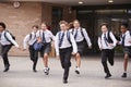 Group Of High School Students Wearing Uniform Running Out Of School Buildings Towards Camera At The End Of Class Royalty Free Stock Photo