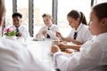 Group Of High School Students Wearing Uniform Sitting Around Table And Eating Lunch In Cafeteria Royalty Free Stock Photo