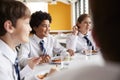 Group Of High School Students Wearing Uniform Sitting Around Table And Eating Lunch In Cafeteria Royalty Free Stock Photo
