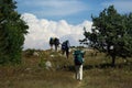 A group of hikers reach the top of a hill and go over to the horizon