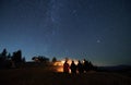 Group of hikers sitting near campfire under night starry sky. Royalty Free Stock Photo