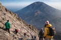 Group of hikers trekking on a rocky volcanic slope inspired by Mount Merapi, with Mount Merbabu visible in the background Royalty Free Stock Photo