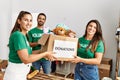 Group of hispanic volunteers smiling happy holding box with toys to donate at charity center Royalty Free Stock Photo