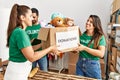 Group of hispanic volunteers smiling happy holding box with toys to donate at charity center Royalty Free Stock Photo