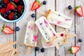 Mixed berry yogurt popsicles over a white wood background Royalty Free Stock Photo