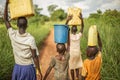 Group if young African kids walking with buckets and jerrycans on their head as they prepare to bring clean water back to their vi