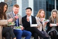 Group of international businesspeople eating lunch at city street. Royalty Free Stock Photo