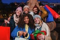 Group of international friends with shopping bags and a christmas gift smiling, laughing and looking at camera. Happy Royalty Free Stock Photo