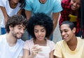 Group of international young adults looking at phone Royalty Free Stock Photo