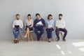 Group of job seekers sitting on chairs in row with resumes and waiting in line for interview