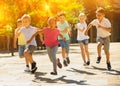 Group of joyful children running down the city street