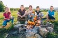 Group of Kids - Boys and girls cheerfully smiling and roasting sausages on long sticks over a campfire flame. Outdoor active time Royalty Free Stock Photo