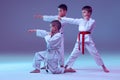 Group of kids, different boys, taekwondo athletes in white doboks in action on lilac color background. Concept