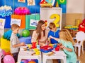 Group of kids with female teacher painting together .