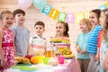 Group of kids having fun by festive table at birthday party Royalty Free Stock Photo