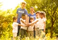 Group of kids joining hands with volunteers in park Royalty Free Stock Photo