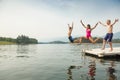 Group of kids jumping off the dock into the lake together during a fun summer vacation. Royalty Free Stock Photo