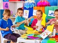 Group kids make applique of colored paper in kindergarten .