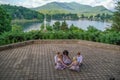 Group of kids praying near a cross surrounded by a lake and hills covered in forests