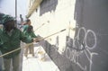 A group of kids repainting the side of a building defaced by graffiti