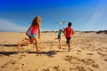 Group of kids run away with color kite on a beach Royalty Free Stock Photo